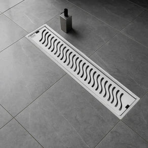 Decorative floor drain cover with wavy pattern on a tiled floor